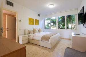 a white bedroom with a bed and a window at Modern Ground Level, 4 BR condo in Palm-Eagle Beach