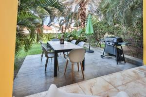 a patio with a table and chairs and a grill at Modern Ground Level, 4 BR condo in Palm-Eagle Beach