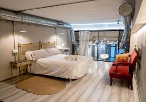 a bedroom with a large bed and a red chair at Loft artístico Espacio Lirola Centro in Granada