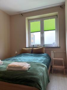 a bedroom with a bed and two windows with green blinds at Rodzinna Przystań in Białystok