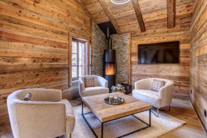 a living room with two chairs and a table and a tv at Central High-End Duplexes, Sauna and Stove in Champéry