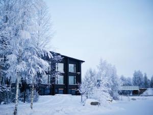 ein schneebedecktes Haus mit Bäumen davor in der Unterkunft Jauri Resort in Kemijärvi