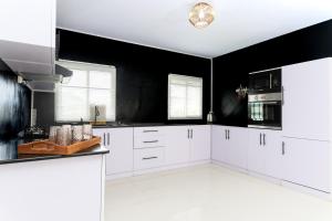 a white kitchen with black walls and white cabinets at Sitraka Résidence in Mahitsy