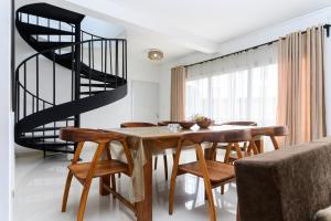 a dining room with a wooden table and a spiral staircase at Sitraka Résidence in Mahitsy +7 photos