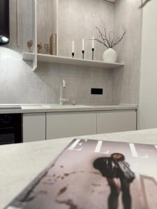 a kitchen with a table with a reflection of a person at Mediteran Line Apartman 1 in Sombor