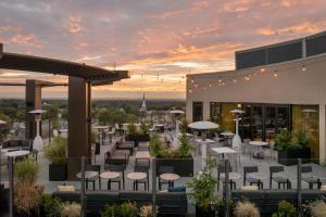 a rooftop patio with tables and chairs at sunset at The MC, Autograph Collection in Montclair