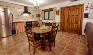 a kitchen with a table and chairs and a refrigerator at Alameda II con CHIMENEA Salòn y BARBACOA en patio in Curiel de Duero