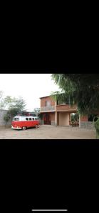 a red and white bus parked in front of a building at Raimy Sumaq in Arenillas