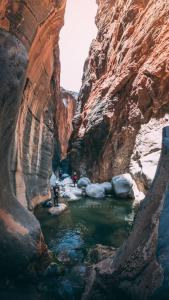 a group of people standing in a river in a canyon at Seet Room in Bilād Sayt