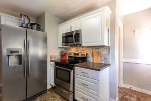 a kitchen with white cabinets and a stainless steel refrigerator at Copper Voyage, Fenced Backyard in Coeur d'Alene