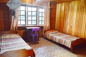 a bedroom with two beds and a desk and a window at Labang Guesthouse Bario in Bario