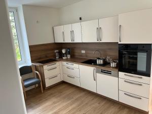 a kitchen with white cabinets and black appliances at Kaiserlich schlafen in der alten Post in Oelsnitz