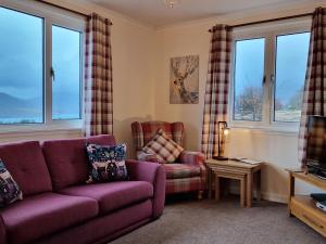 a living room with a purple couch and two chairs at Little Loch View in Durnamuck