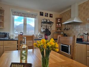 a kitchen with a table with a vase of yellow flowers at Little Loch View in Durnamuck