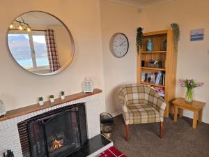 a living room with a fireplace and a mirror at Little Loch View in Durnamuck