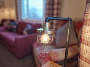 a lamp with a light in a living room at Little Loch View in Durnamuck