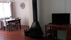 a living room with a fireplace and a table with a television at Under The Oak in Underberg