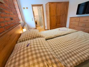 a bedroom with two beds and a tv on a brick wall at Pension Kronenburghof in Erfurt +40 photos