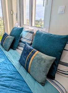 Ein Bett mit blauen Kissen steht neben einem Fenster. in der Unterkunft Villa Debriz Apartment in Stréfion + 34 Fotos