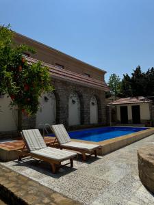 two chairs and a swimming pool in front of a house at Bilgeh Old House Villa in Baku