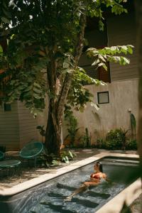 a woman swimming in a pool next to a tree at Mar Botánico - Avellanas Beach Hotel in Playa Avellana