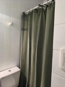 a bathroom with a green shower curtain and a toilet at Monoambiente en pleno centro de Adrogué in Adrogué +15 photos
