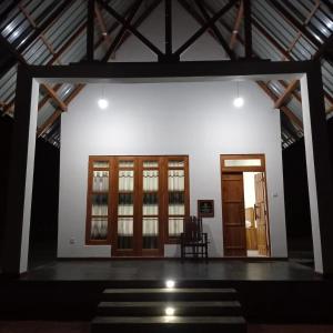 a room with a white wall and wooden doors at The Corel Waves Inn in Kalkudah