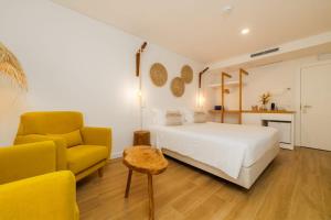 a bedroom with a white bed and a yellow chair at Alojamento White Rose Boutique in Zambujeira do Mar +51 photos