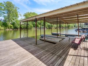 a wooden deck with two chairs on the water at Jax Joint - Pet Friendly - Perfect Family Vacation Spot! in Crane Hill