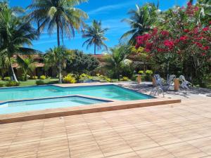 a swimming pool in a resort with palm trees at Pousada Taba de Canes in Canavieiras
