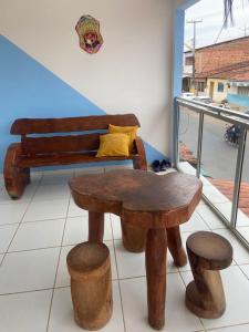 a room with a bench and a table and stools at Luar Dos Milagres in São Miguel dos Milagres