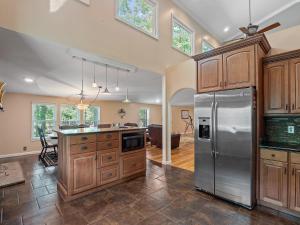 a kitchen with wooden cabinets and a stainless steel refrigerator at Rocking W - Screened In Porch And Lakeside Fire Pit! in Double Springs