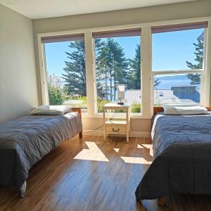 two beds in a room with a large window at Saltwater Beach Home with Ocean View in Des Moines