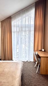 a bedroom with a bed and a desk and a window at Yu-home in Mukacheve
