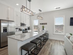 a kitchen with white cabinets and a counter with bar stools at Mallard Pointe 100 - Luxury Condo- Conveniently Located! in Cullman