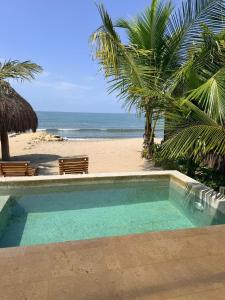 a swimming pool next to a beach with palm trees at Luxury Suite frente de Mar Piscina Restaurante y Bar in San Silvestre