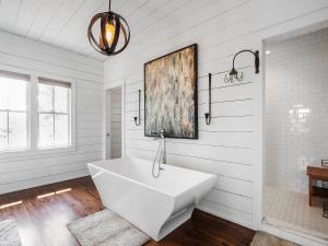 a bathroom with a white tub and a painting on the wall at Central Perk - Pet Friendly, Luxury Cabin Feel, Kayaksand Coffee! in Crane Hill +26 photos