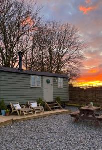 a house with chairs and a picnic table and a sunset at The Hut at Claston in Stoke Edith