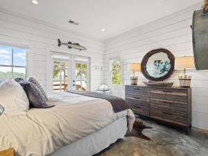 a bedroom with a bed and a dresser with a mirror at Central Perk - Pet Friendly, Luxury Cabin Feel, Kayaksand Coffee! in Crane Hill