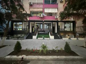a pink building with a sign in front of it at Swiss Lux apartments in Durrës