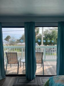 a bedroom with a view of a deck with two chairs at Park Place Condo 227 in Cedar Key +1 photo