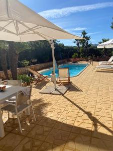 a white umbrella sitting next to a swimming pool at Villa Verabetta in San Vito lo Capo