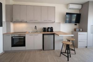 a kitchen with white cabinets and a sink and stools at 3L Apartment and Studio in Nikiana +24 photos