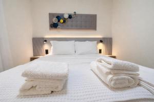 a bedroom with a white bed with towels on it at 3L Apartment and Studio in Nikiana