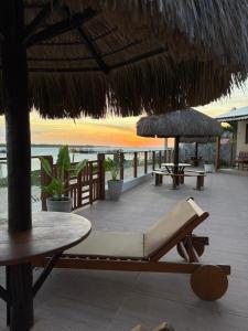 a lounge chair under a straw umbrella on the beach at Pousada Rio Aratuá in Galinhos