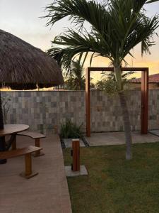 a patio with a table and a palm tree at Pousada Rio Aratuá in Galinhos