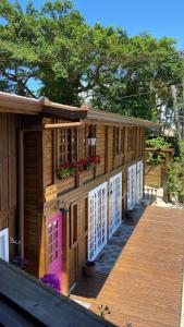 a wooden house with a pink door on a deck at Vilarejo Hospedagem - Encantadas in Ilha do Mel