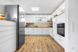 a kitchen with white cabinets and a wooden floor at Ferienhaus Ankerplatz St Peter-Ording in Böhl