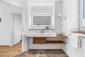 a white bathroom with a sink and a window at Ferienhaus Ankerplatz St Peter-Ording in Böhl +19 photos