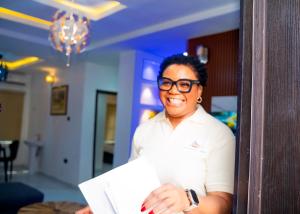 a woman wearing glasses standing in a room at Riverside Nest Owerri Ltd in Owerri